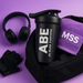 The ABE shaker is peeking out of a black gym bag with a MySupplementShop (MSS) purple towel and headphones in the background.