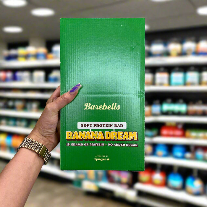 Close-up of (Barebells Soft Protein Bar 12x55g) held up inside My Supplement Shop, clearly showing the front label in a Sports Nutrition setting.